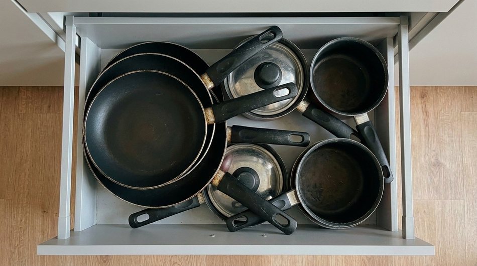 Überfüllte Küchenschublade, feste Pfannengriffe blockieren kreuz und quer den Platz